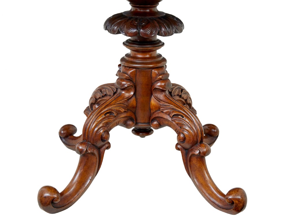 A 19th-century mahogany oval centre table featuring a flame mahogany veneered top, a scalloped apron, and a heavily carved tripod pedestal base with scroll feet. View II