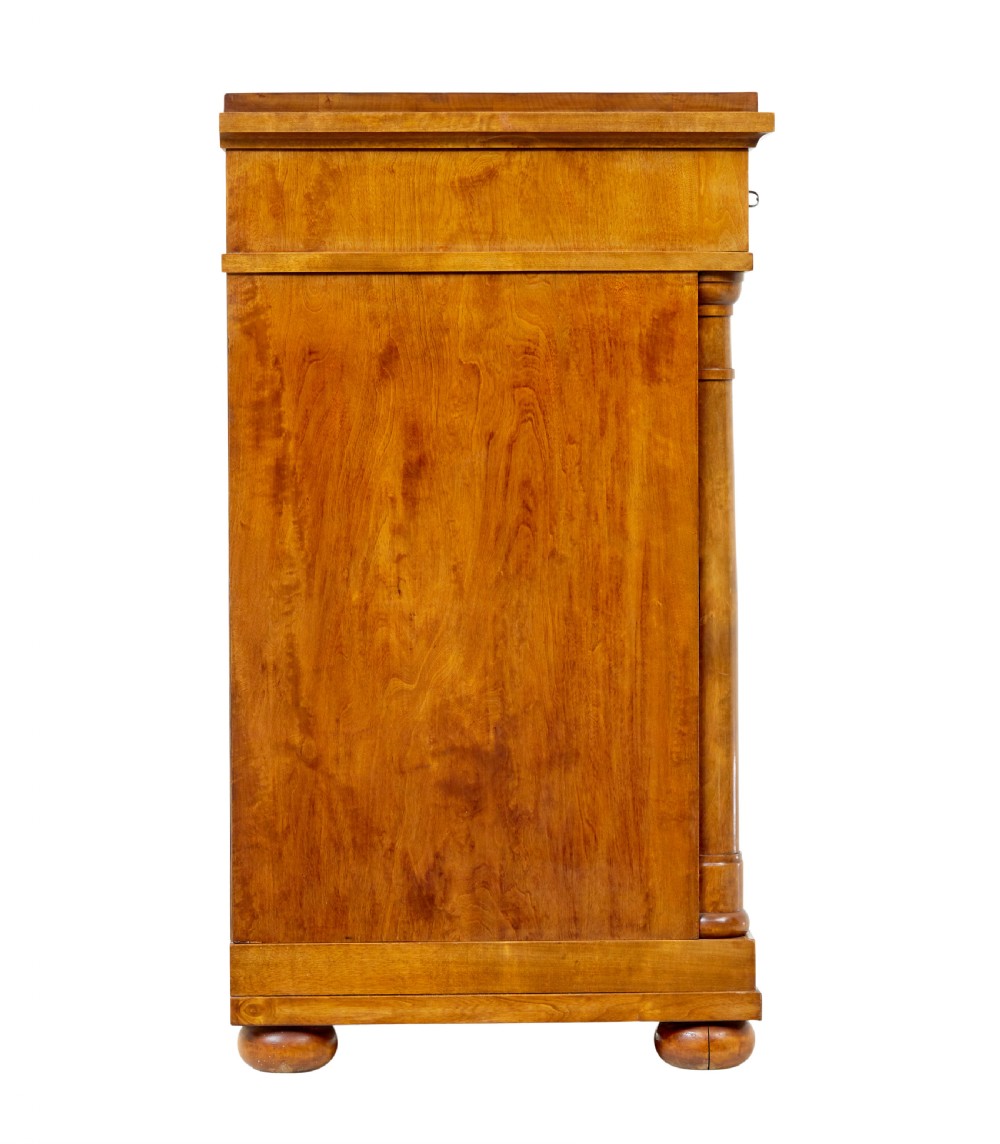 A 19th-century birch Empire Revival chest of drawers featuring architectural side columns, recessed panelled drawers, and turned bun feet. View VII