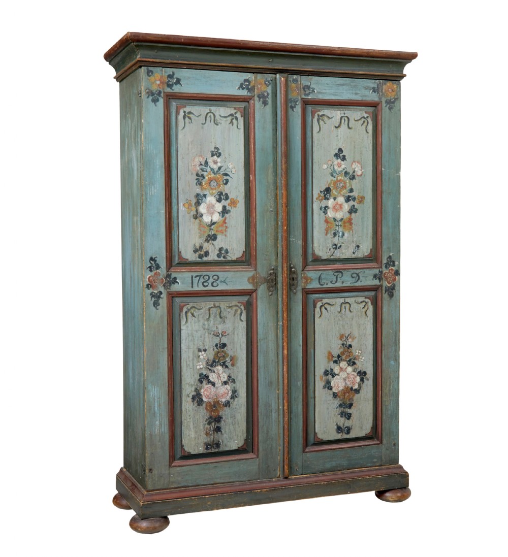 A Swedish hand-painted blue pine cupboard with panelled doors featuring floral motifs, red trim, a dated inscription from 1788, and bun feet.
