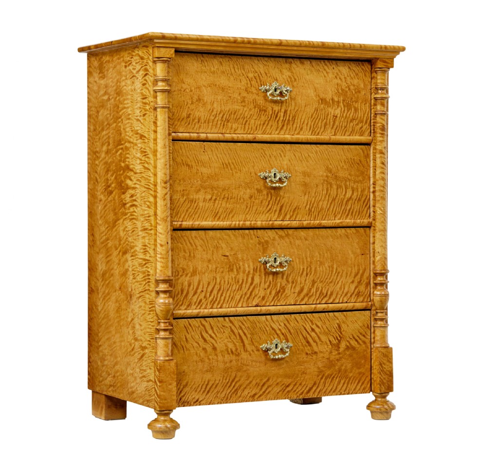 A nineteenth-century Swedish chest of four drawers crafted from figure-rich tiger birch with turned side columns and ornate brass escutcheons.