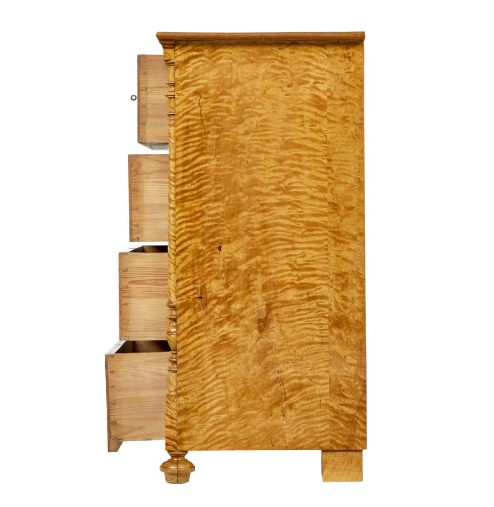 A nineteenth-century Swedish chest of four drawers crafted from figure-rich tiger birch with turned side columns and ornate brass escutcheons. View V
