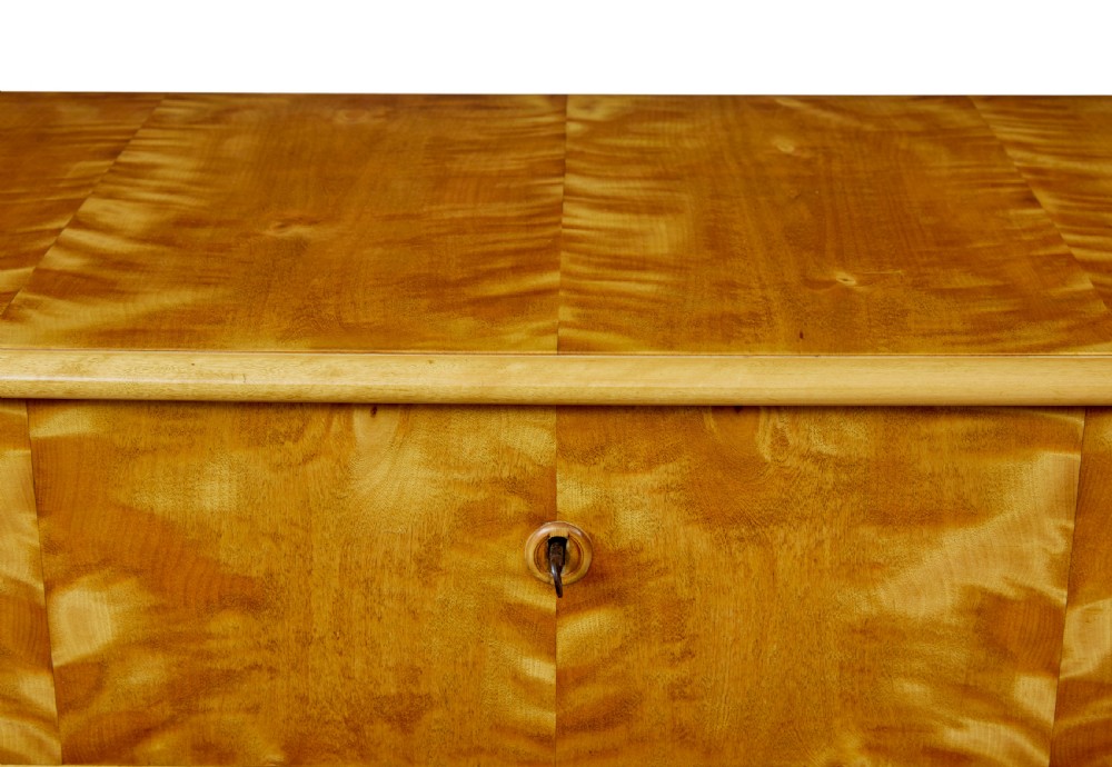 A 19th-century Swedish chest of four drawers crafted from golden flame birch veneer with simple keyhole escutcheons and square legs. View VII