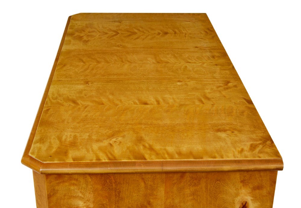 A 19th-century Swedish chest of four drawers crafted from golden flame birch veneer with simple keyhole escutcheons and square legs. View IX