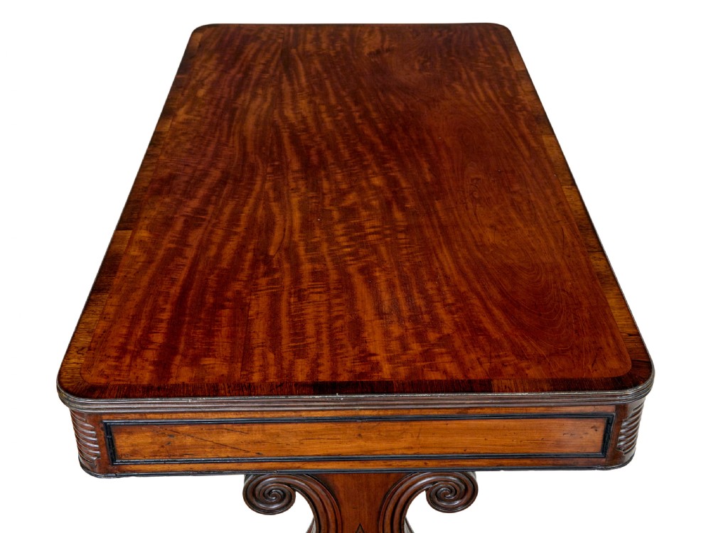 A 19th-century William IV mahogany library desk featuring three frieze drawers with brass knobs, carved scroll end supports, and a turned stretcher on brass castors. View VIII