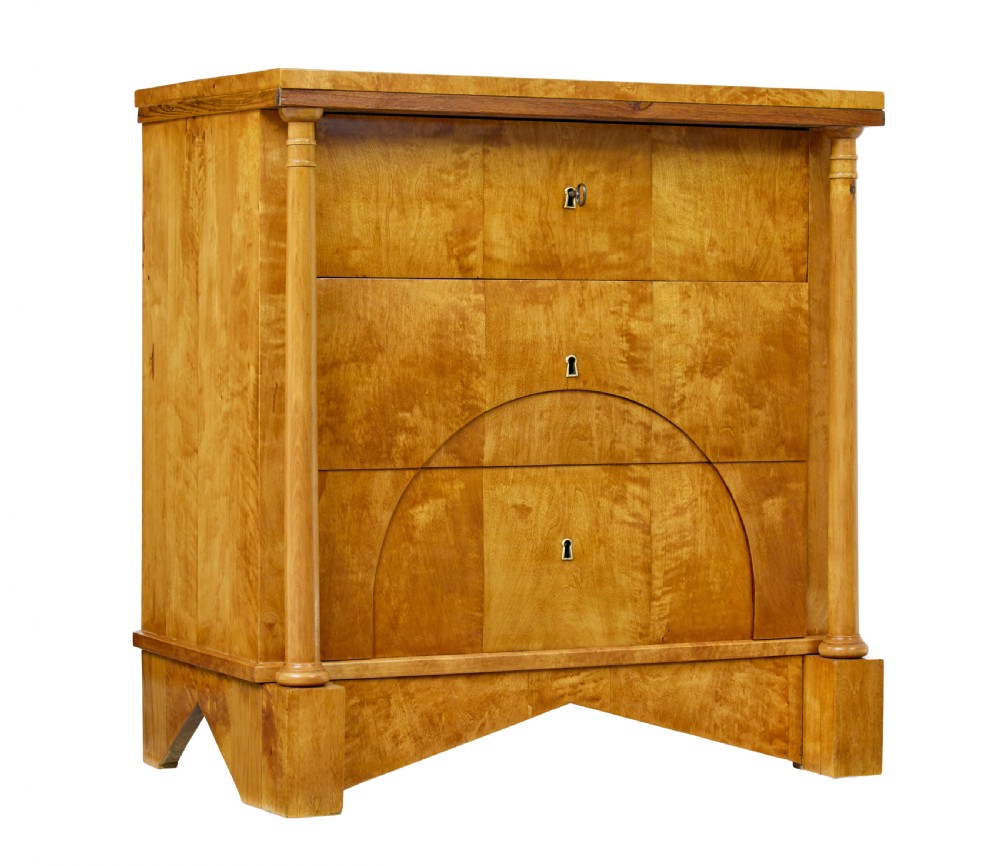 A 19th-century Swedish Empire satin birch chest of drawers featuring three drawers, flanking turned columns, an arched lower veneer panel, and angular block feet.