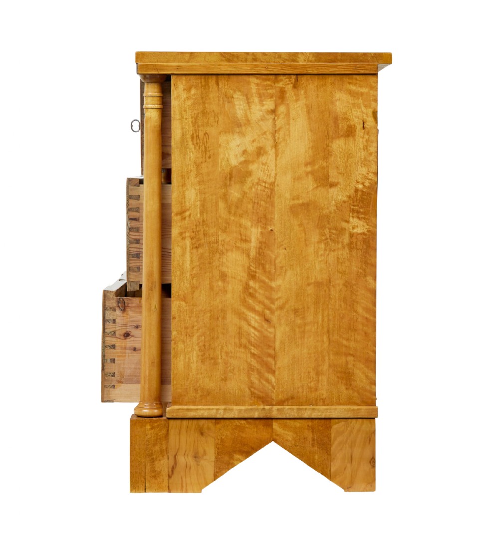 A 19th-century Swedish Empire satin birch chest of drawers featuring three drawers, flanking turned columns, an arched lower veneer panel, and angular block feet. View V