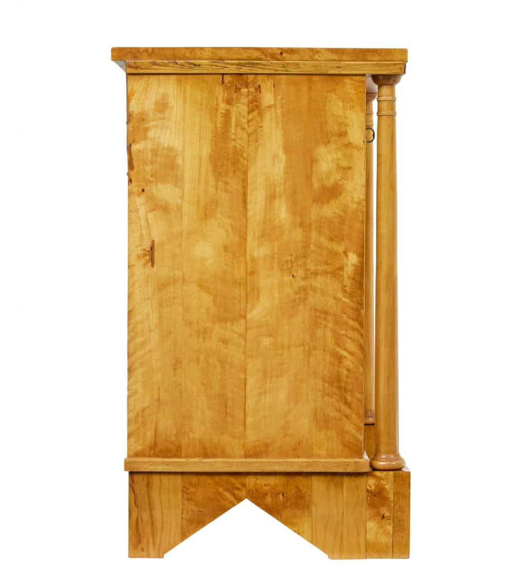 A 19th-century Swedish Empire satin birch chest of drawers featuring three drawers, flanking turned columns, an arched lower veneer panel, and angular block feet. View VII