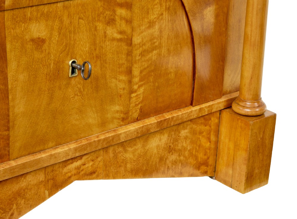A 19th-century Swedish Empire satin birch chest of drawers featuring three drawers, flanking turned columns, an arched lower veneer panel, and angular block feet. View IX