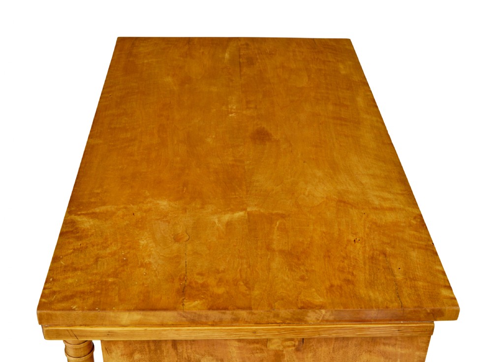 A 19th-century Swedish Empire satin birch chest of drawers featuring three drawers, flanking turned columns, an arched lower veneer panel, and angular block feet. View XI
