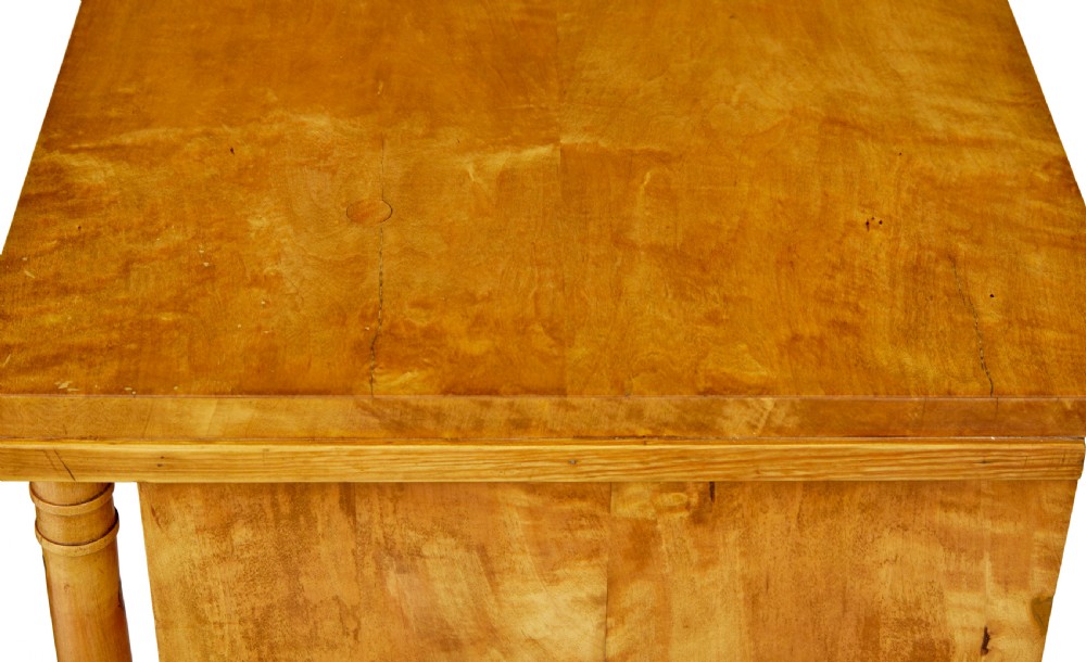 A 19th-century Swedish Empire satin birch chest of drawers featuring three drawers, flanking turned columns, an arched lower veneer panel, and angular block feet. View XII
