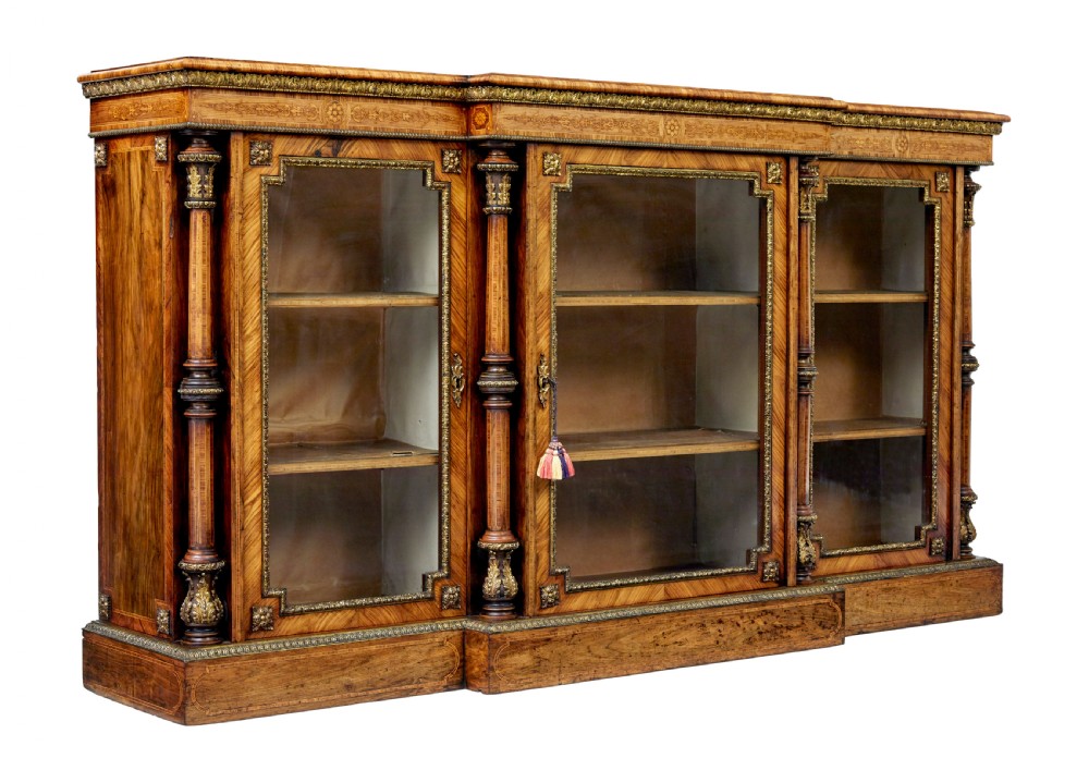 A mid-19th century Victorian walnut credenza featuring three glass-fronted doors, intricate marquetry inlay, and ornate gilt-bronze mounts.