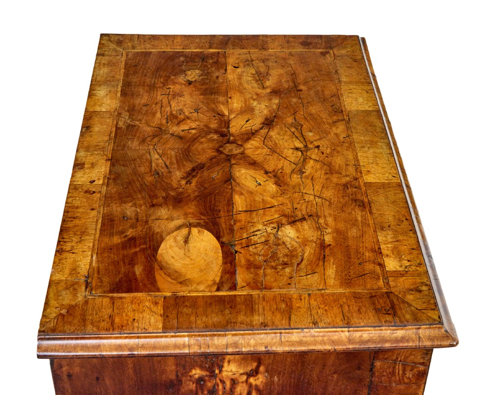An eighteenth-century Queen Anne walnut kneehole desk featuring figured walnut veneers, brass drop handles, a central recessed cupboard, and bracket feet. View II