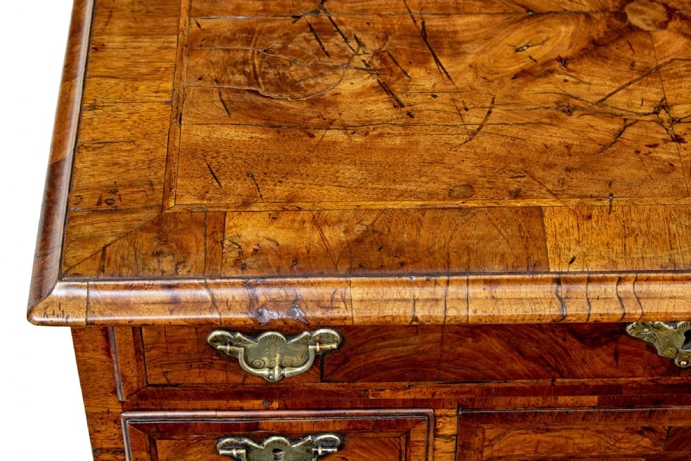An eighteenth-century Queen Anne walnut kneehole desk featuring figured walnut veneers, brass drop handles, a central recessed cupboard, and bracket feet. View V