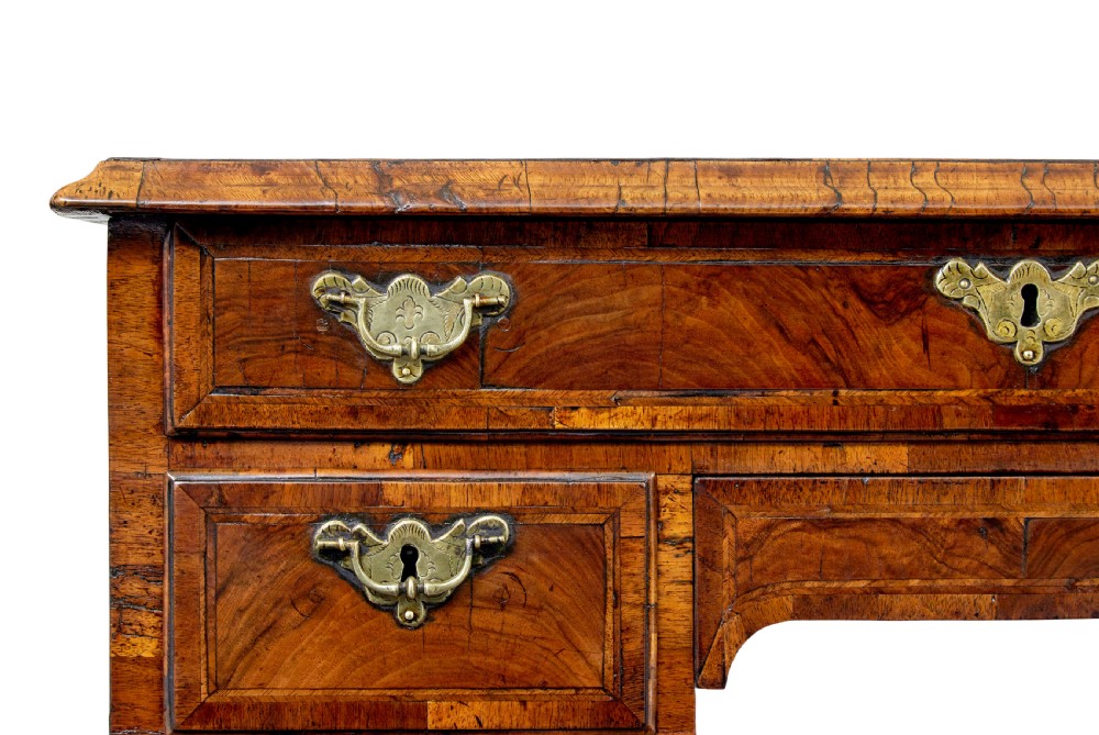 An eighteenth-century Queen Anne walnut kneehole desk featuring figured walnut veneers, brass drop handles, a central recessed cupboard, and bracket feet. View VI