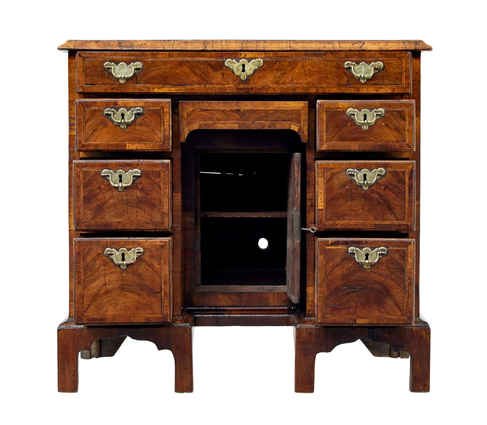 An eighteenth-century Queen Anne walnut kneehole desk featuring figured walnut veneers, brass drop handles, a central recessed cupboard, and bracket feet. View IX