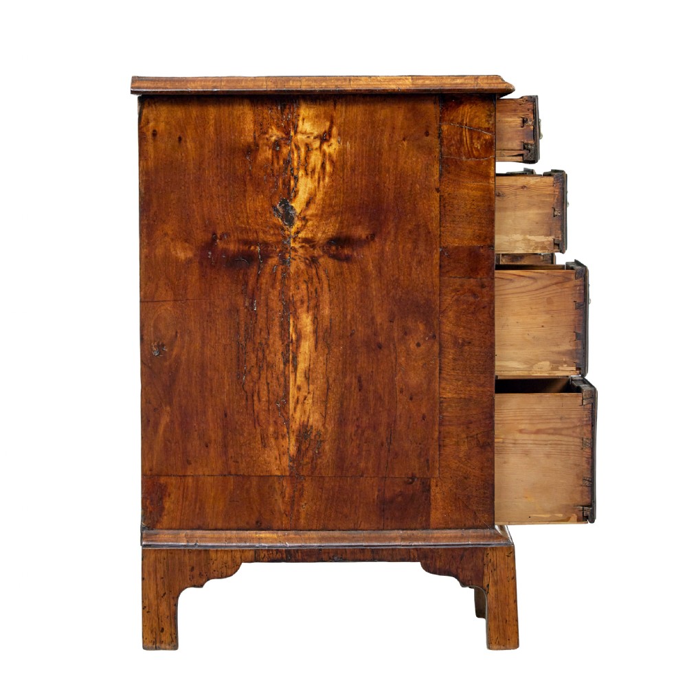An eighteenth-century Queen Anne walnut kneehole desk featuring figured walnut veneers, brass drop handles, a central recessed cupboard, and bracket feet. View X