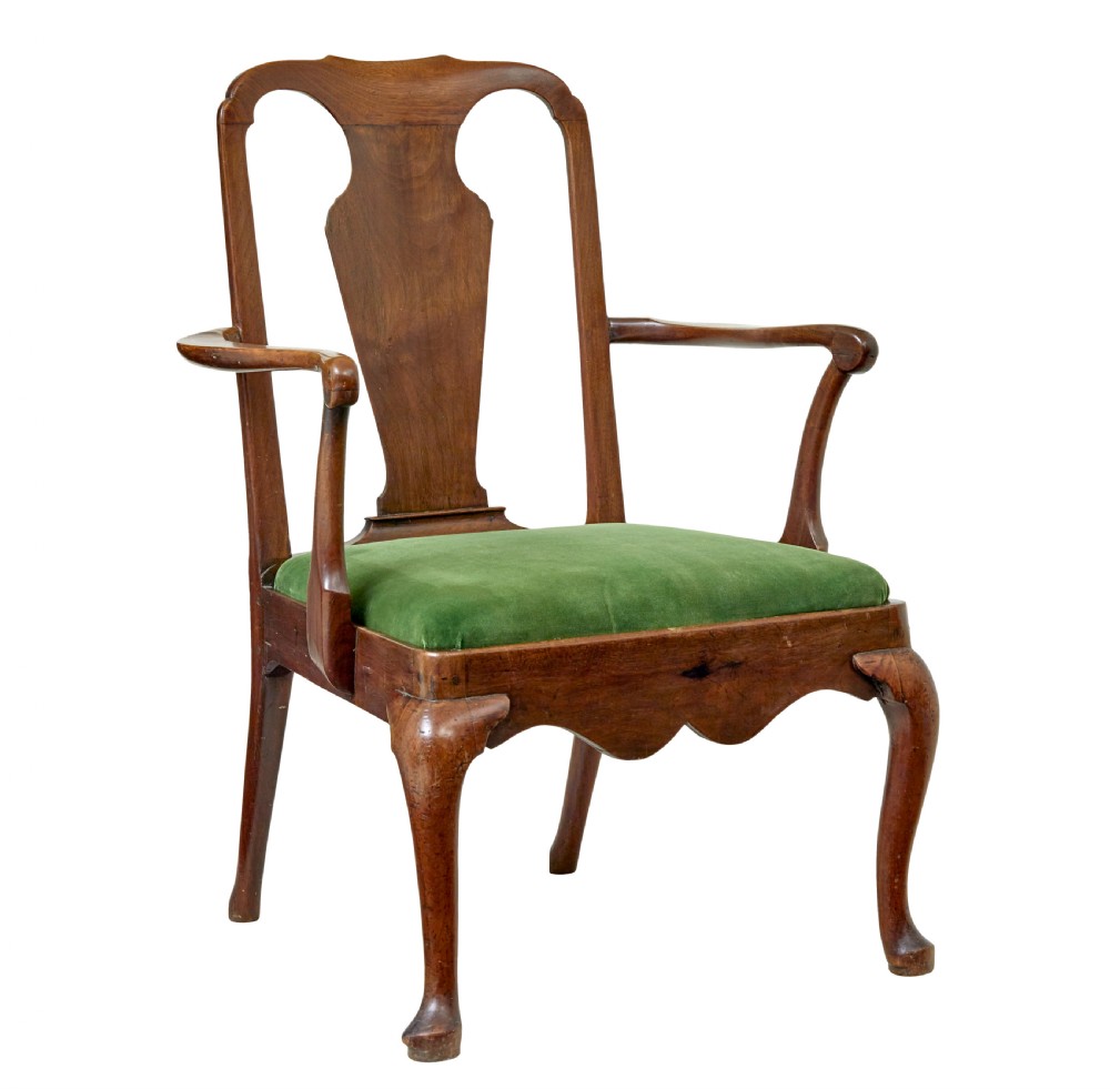 An 18th-century walnut open armchair featuring a contoured vase splat back, curved arms, a green velvet seat, and front cabriole legs with pad feet.