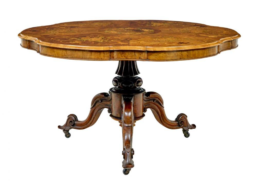 A 19th-century Victorian walnut centre table featuring intricate floral marquetry inlays, a shaped rim, and a carved central pedestal with four scroll legs on castors.