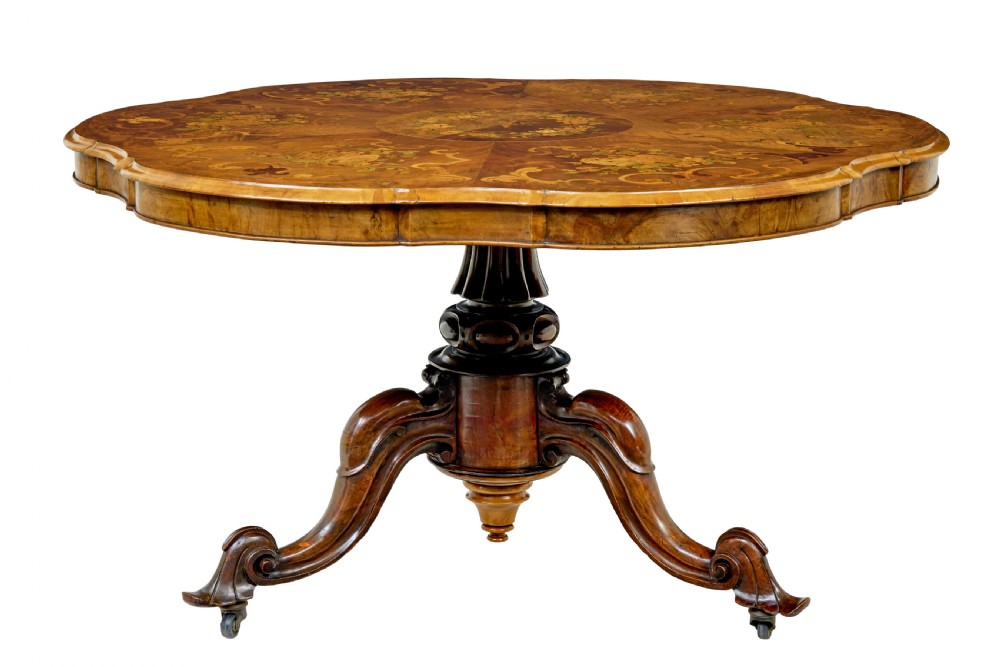 A 19th-century Victorian walnut centre table featuring intricate floral marquetry inlays, a shaped rim, and a carved central pedestal with four scroll legs on castors. View II