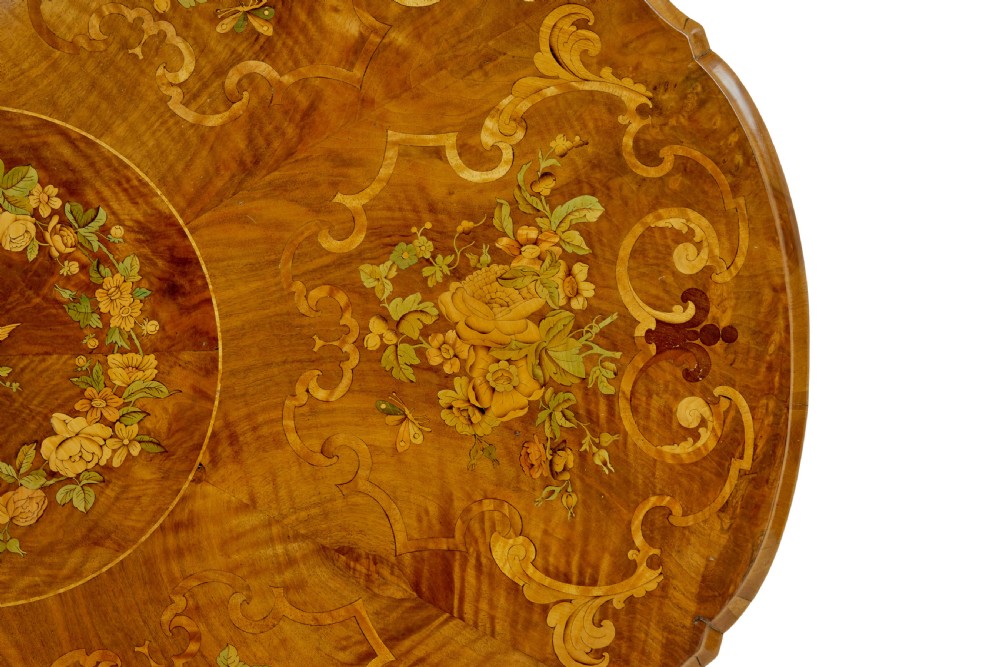 A 19th-century Victorian walnut centre table featuring intricate floral marquetry inlays, a shaped rim, and a carved central pedestal with four scroll legs on castors. View XII