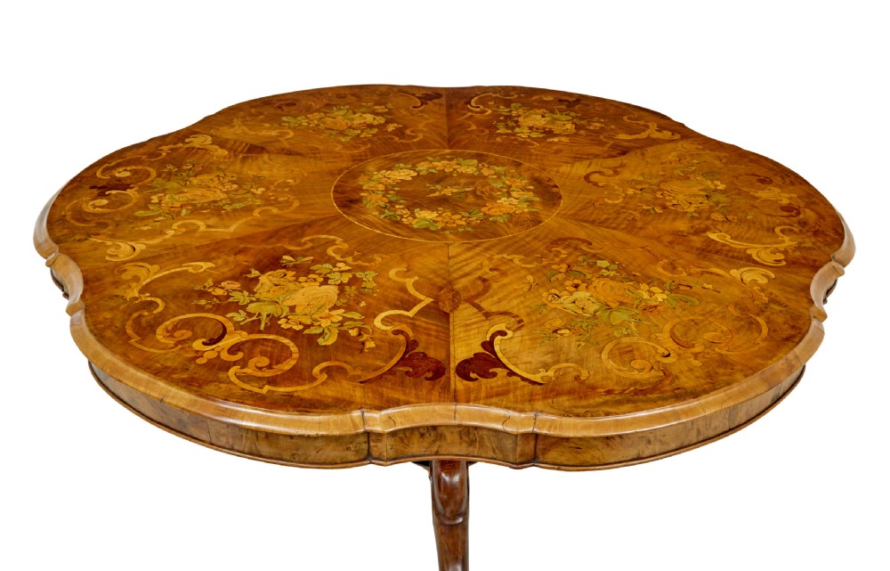 A 19th-century Victorian walnut centre table featuring intricate floral marquetry inlays, a shaped rim, and a carved central pedestal with four scroll legs on castors. View XIV