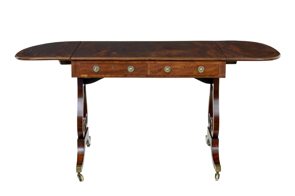 An early 19th-century mahogany sofa table featuring two drop leaves, twin frieze drawers with brass handles, and lyre-shaped scroll legs on brass castors. View III