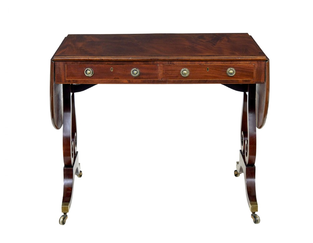 An early 19th-century mahogany sofa table featuring two drop leaves, twin frieze drawers with brass handles, and lyre-shaped scroll legs on brass castors. View VI