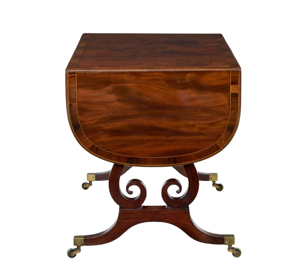 An early 19th-century mahogany sofa table featuring two drop leaves, twin frieze drawers with brass handles, and lyre-shaped scroll legs on brass castors. View VII