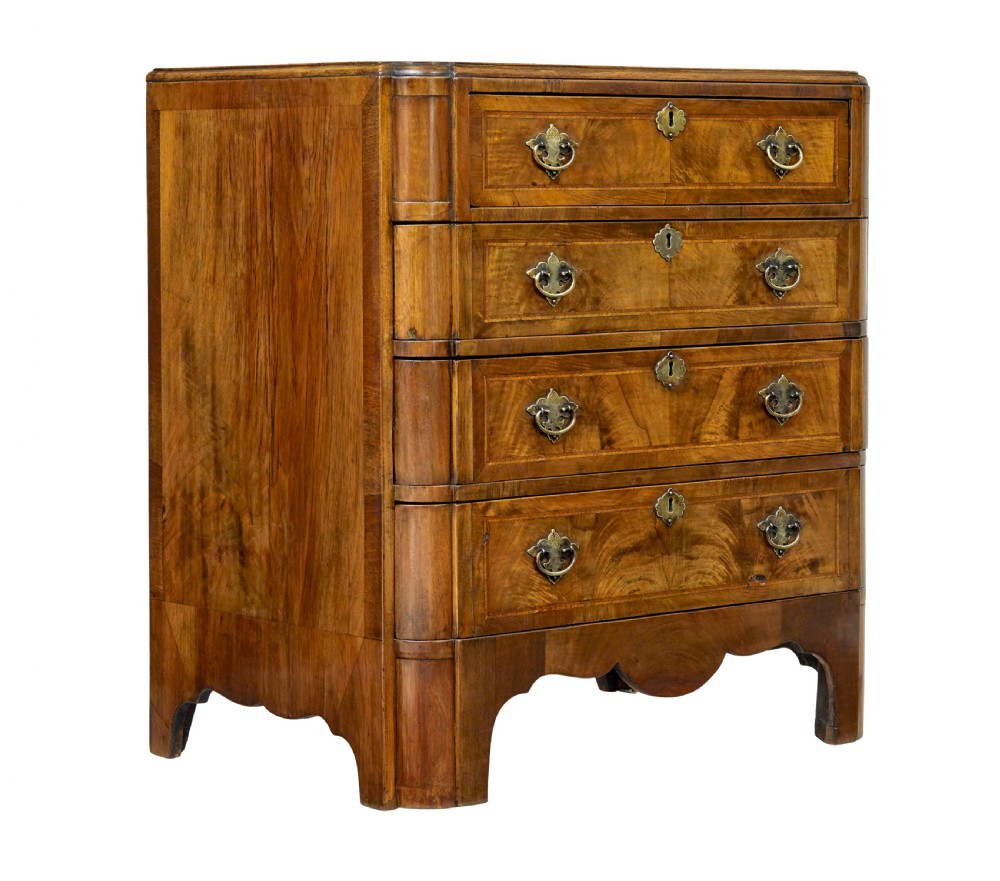 A four-drawer walnut chest featuring figured wood veneers, shaped bottom apron, brass handles, and rounded front corners.