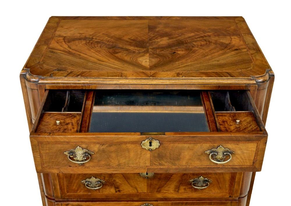 A four-drawer walnut chest featuring figured wood veneers, shaped bottom apron, brass handles, and rounded front corners. View VI