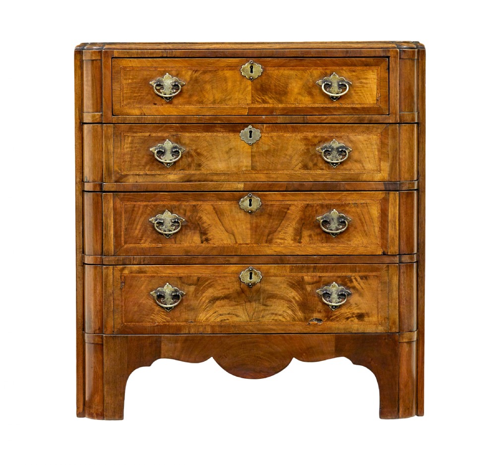 A four-drawer walnut chest featuring figured wood veneers, shaped bottom apron, brass handles, and rounded front corners. View IX