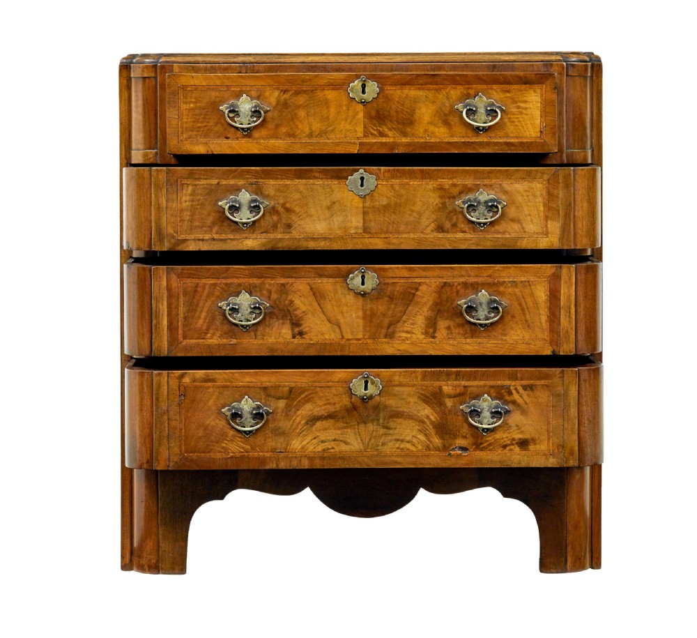 A four-drawer walnut chest featuring figured wood veneers, shaped bottom apron, brass handles, and rounded front corners. View X