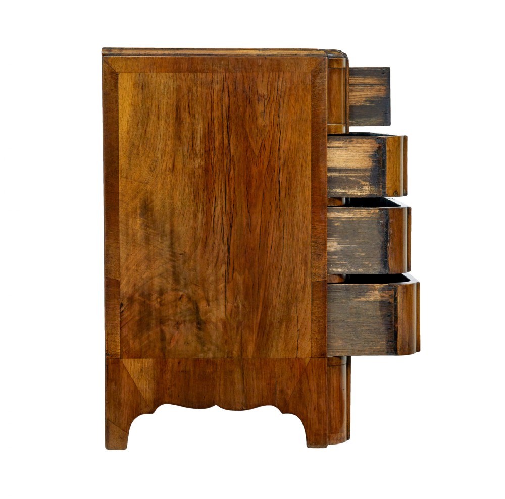 A four-drawer walnut chest featuring figured wood veneers, shaped bottom apron, brass handles, and rounded front corners. View XI