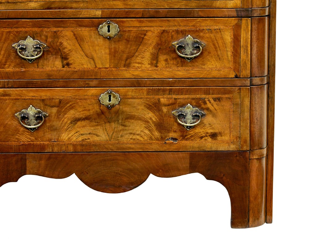 A four-drawer walnut chest featuring figured wood veneers, shaped bottom apron, brass handles, and rounded front corners. View XV