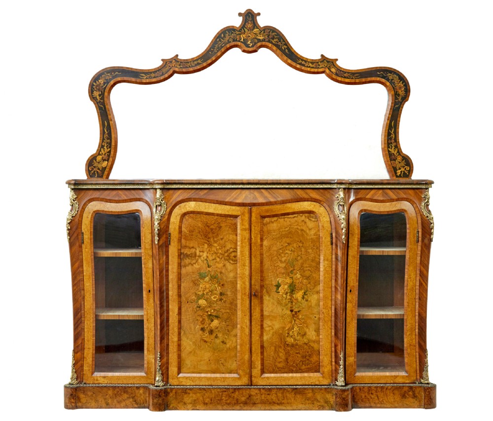 A High Victorian burr walnut credenza featuring floral marquetry inlay, glazed side display cabinets, gilt metal mounts, and a shaped mirror frame superstructure.