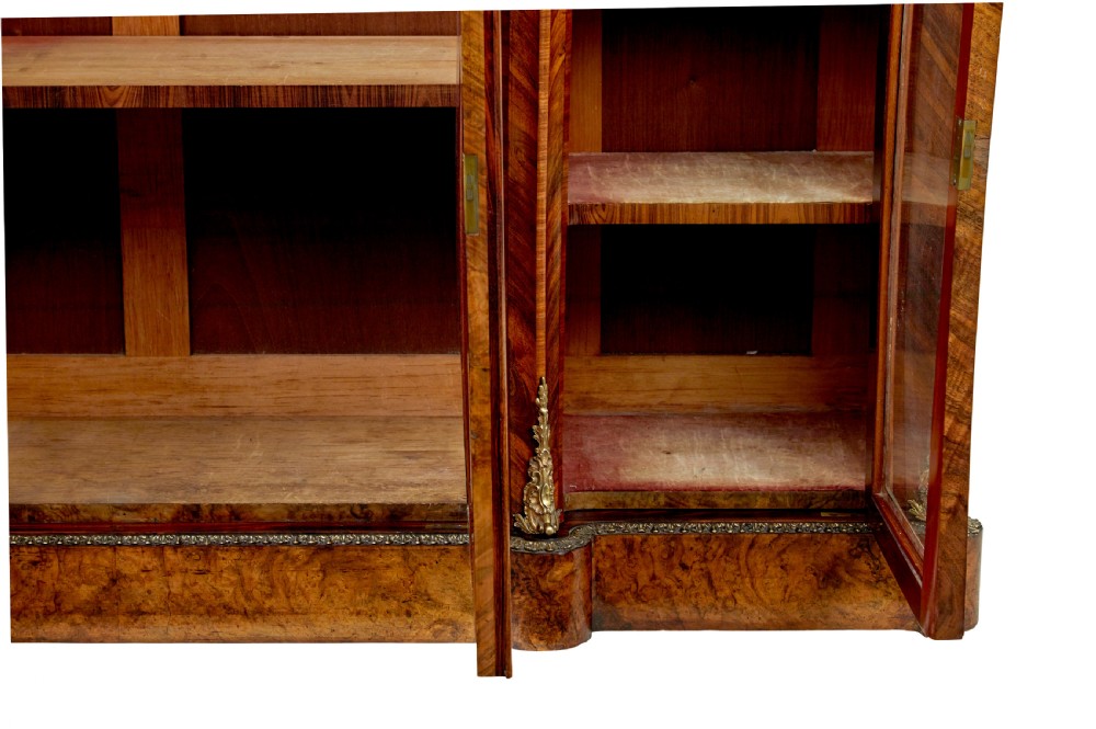 A High Victorian burr walnut credenza featuring floral marquetry inlay, glazed side display cabinets, gilt metal mounts, and a shaped mirror frame superstructure. View III