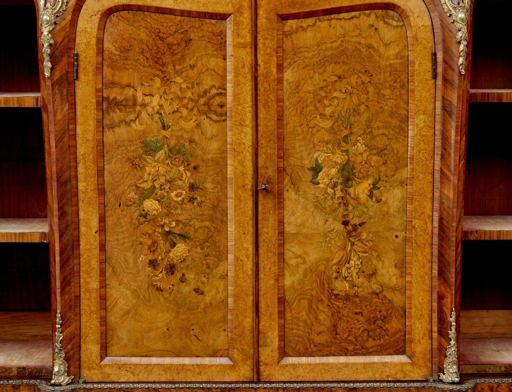 A High Victorian burr walnut credenza featuring floral marquetry inlay, glazed side display cabinets, gilt metal mounts, and a shaped mirror frame superstructure. View V