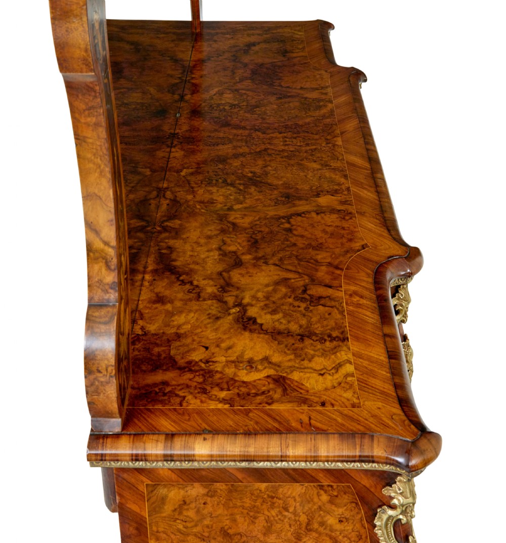 A High Victorian burr walnut credenza featuring floral marquetry inlay, glazed side display cabinets, gilt metal mounts, and a shaped mirror frame superstructure. View IX