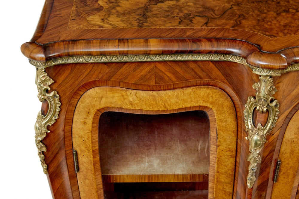 A High Victorian burr walnut credenza featuring floral marquetry inlay, glazed side display cabinets, gilt metal mounts, and a shaped mirror frame superstructure. View XIII