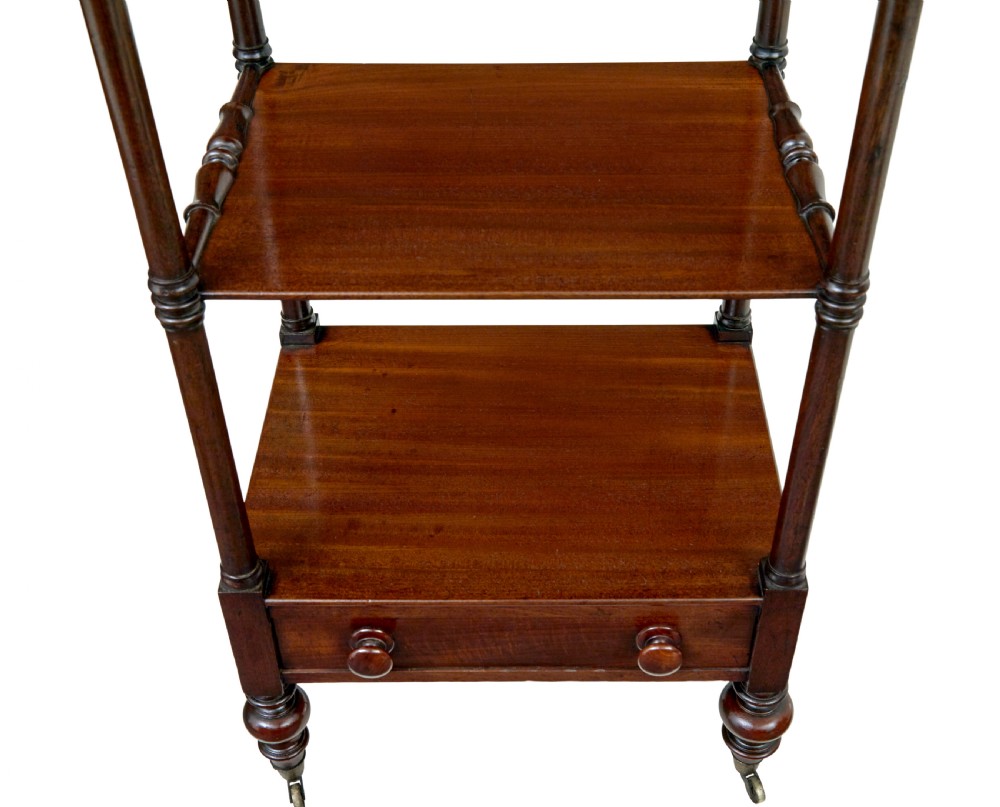 A mid-19th-century mahogany four-tier whatnot featuring slender turned supports, a single base drawer with turned wooden handles, and turned legs with brass castors. View VI