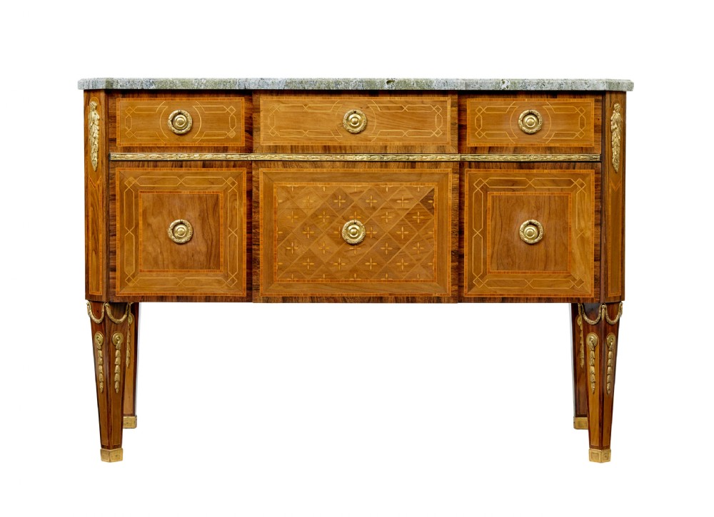 An early 20th-century walnut commode featuring marquetry inlay, gilt bronze mounts, square tapered legs, and a fitted grey marble top. View II