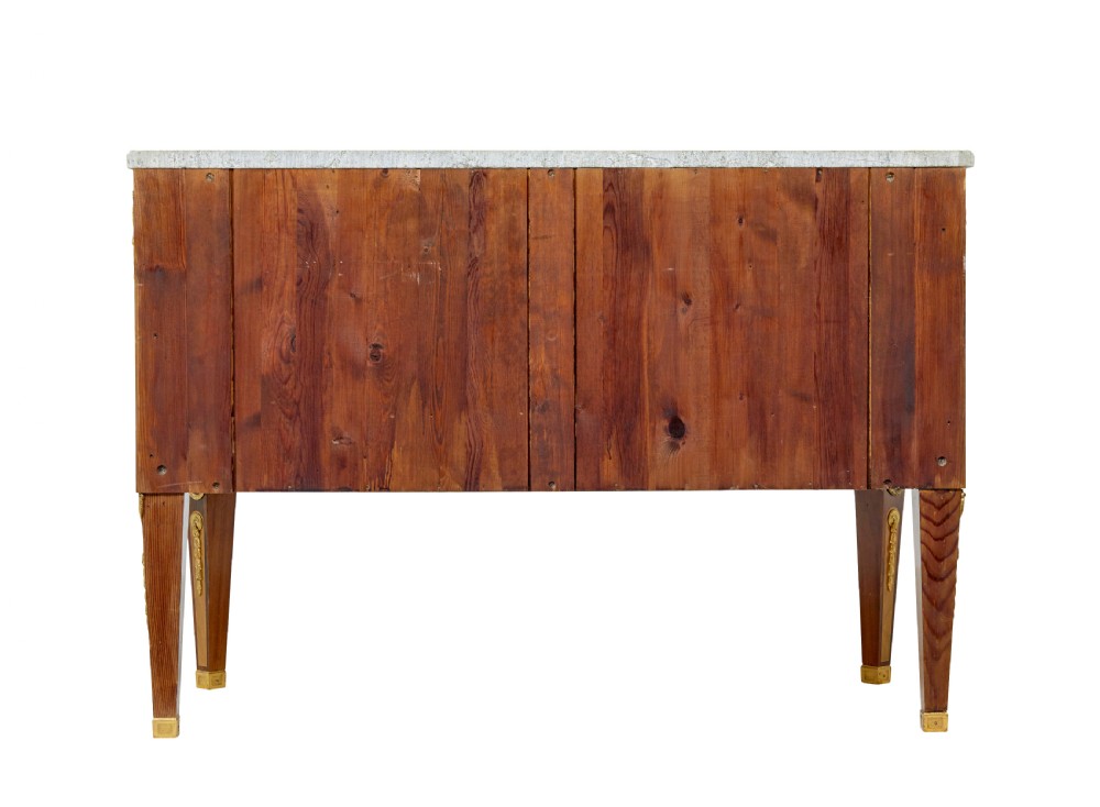 An early 20th-century walnut commode featuring marquetry inlay, gilt bronze mounts, square tapered legs, and a fitted grey marble top. View V