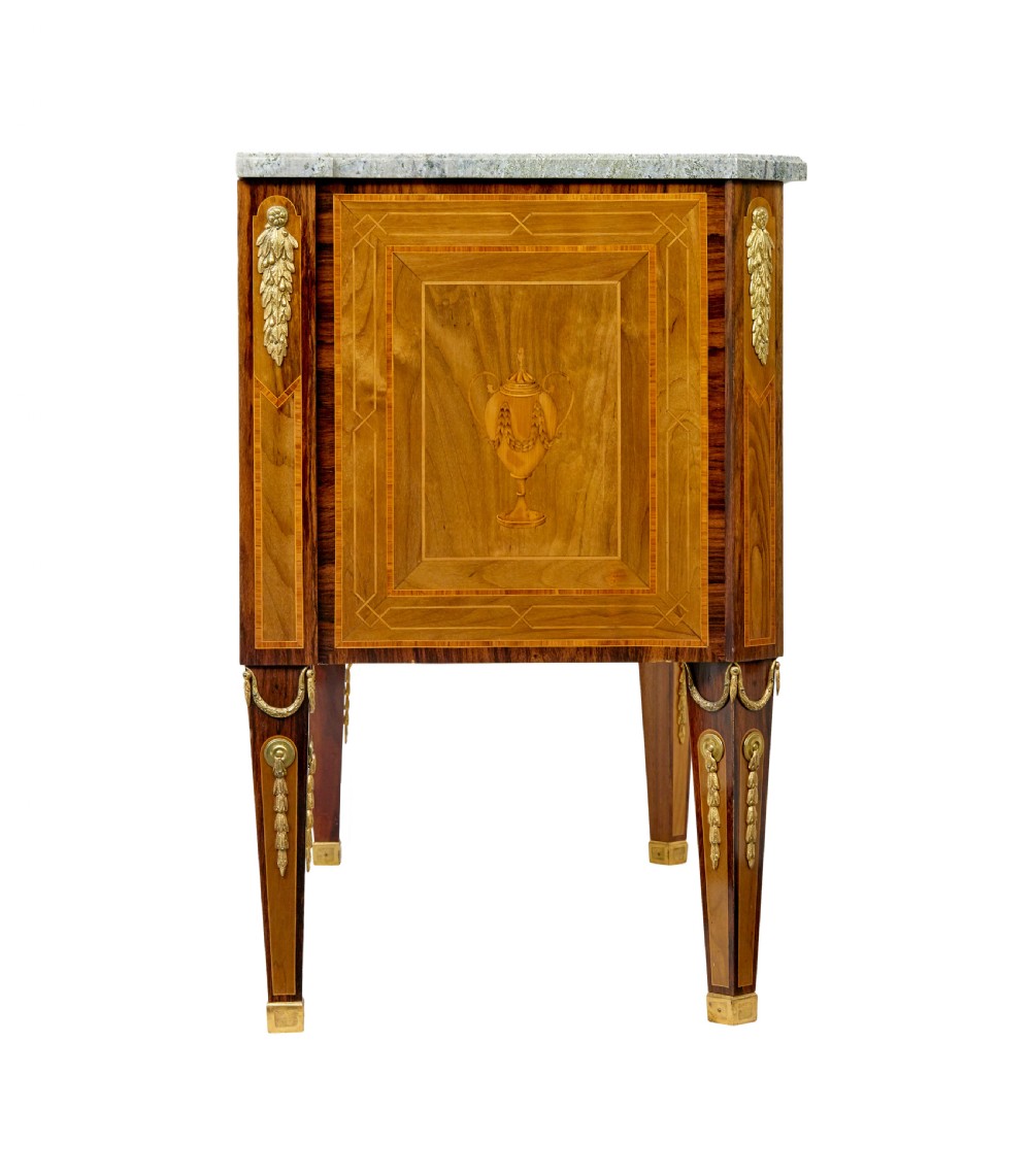 An early 20th-century walnut commode featuring marquetry inlay, gilt bronze mounts, square tapered legs, and a fitted grey marble top. View VI