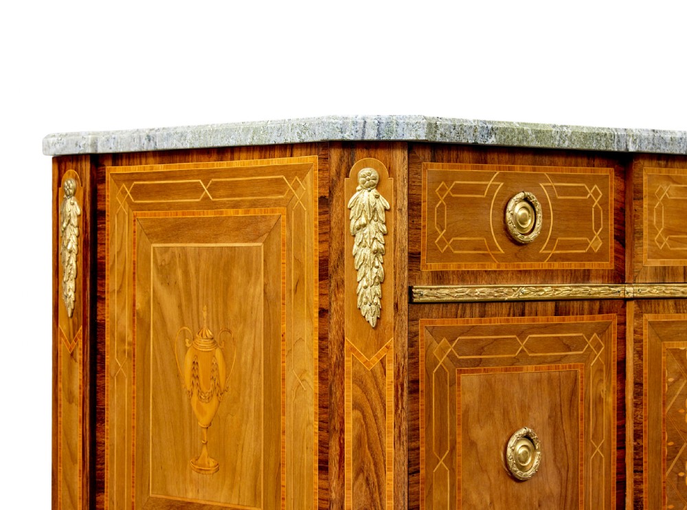 An early 20th-century walnut commode featuring marquetry inlay, gilt bronze mounts, square tapered legs, and a fitted grey marble top. View VII