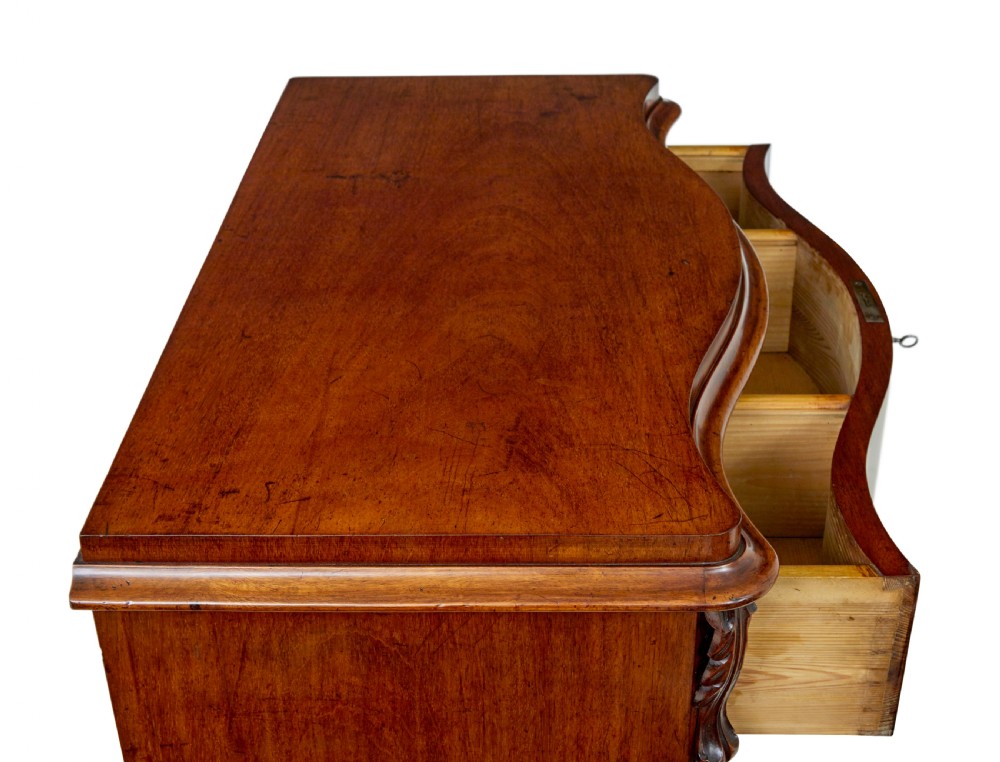 A 19th-century Swedish mahogany chest of drawers with a serpentine front, four drawers, flame timber veneer, carved side accents, and turned feet. View X