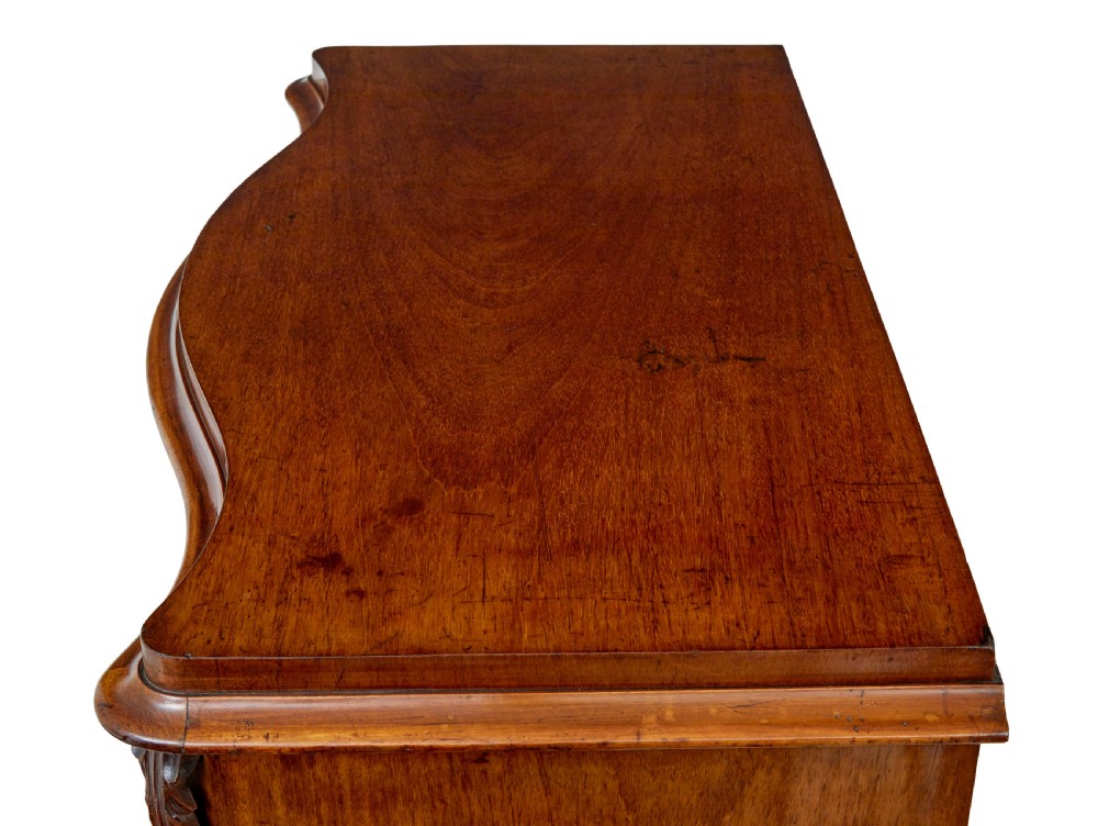 A 19th-century Swedish mahogany chest of drawers with a serpentine front, four drawers, flame timber veneer, carved side accents, and turned feet. View XI