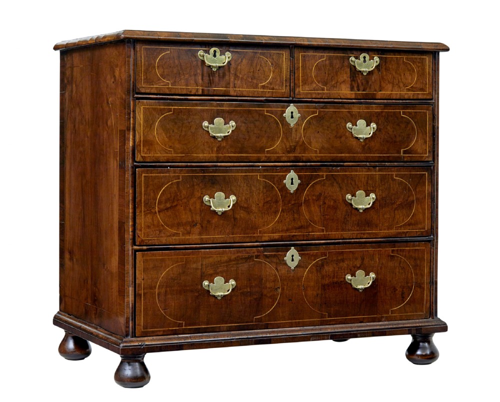 A 17th-century William and Mary walnut chest of drawers with decorative line inlay, brass drop handles, and turned bun feet.