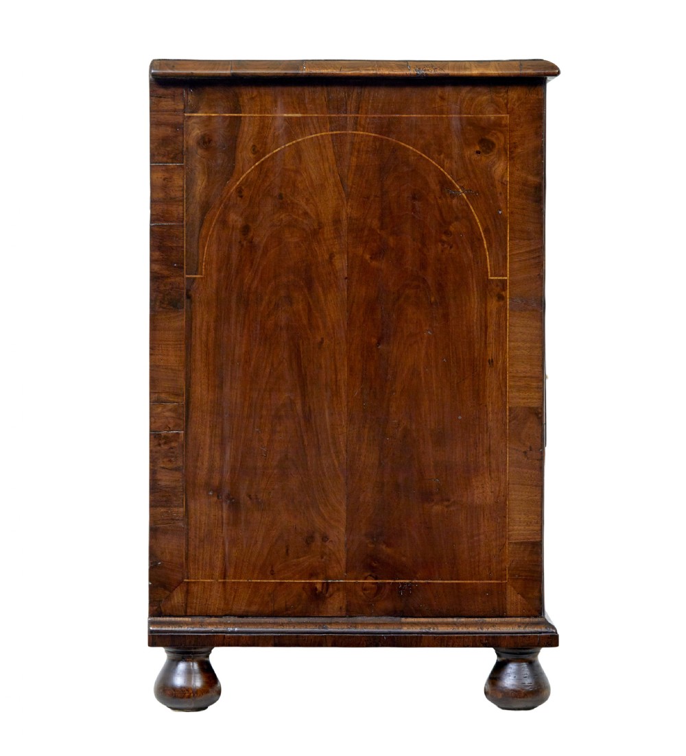 A 17th-century William and Mary walnut chest of drawers with decorative line inlay, brass drop handles, and turned bun feet. View VII