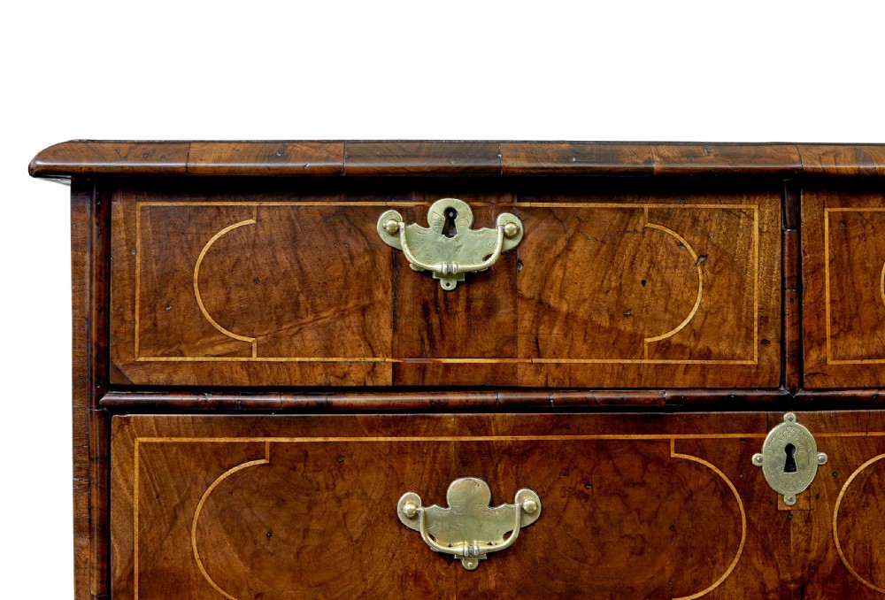 A 17th-century William and Mary walnut chest of drawers with decorative line inlay, brass drop handles, and turned bun feet. View VIII