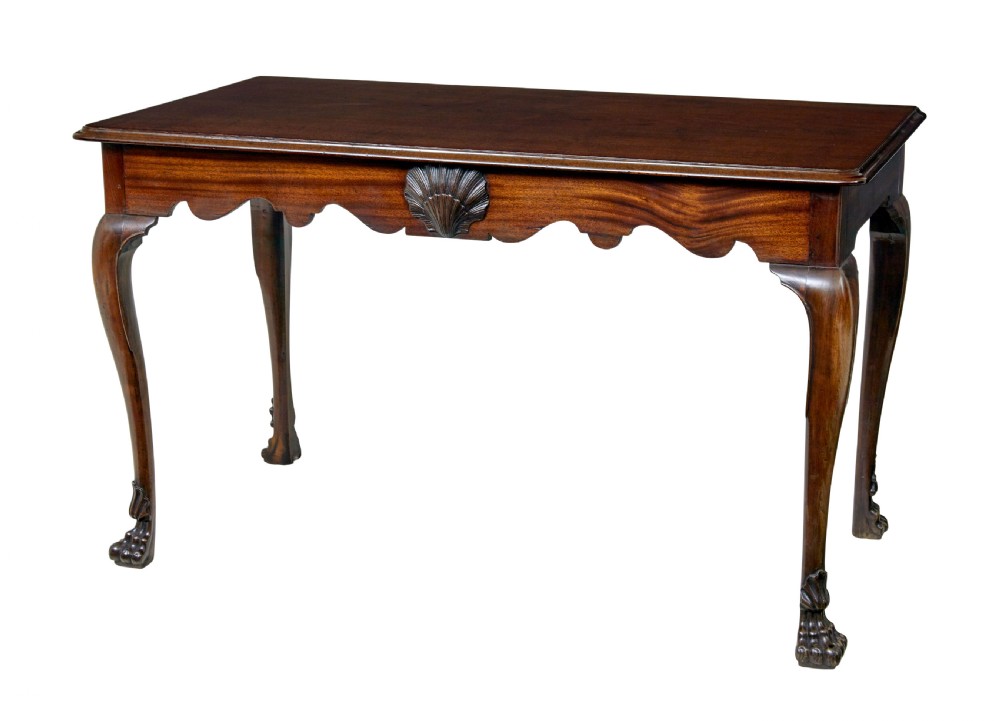 An early nineteenth-century Irish mahogany serving table with a carved central shell motif, scalloped frieze, cabriole legs, and carved feet.